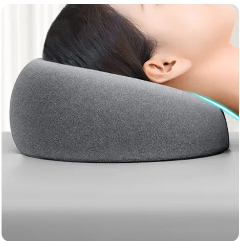 A gray ergonomic memory foam prone pillow is shown resting against a person's ear.