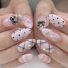 A close-up of hands displaying various pink and white press-on fake nails with heart and polka dot designs.