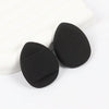 A pair of black latex-free finger puffs resting on a white surface.