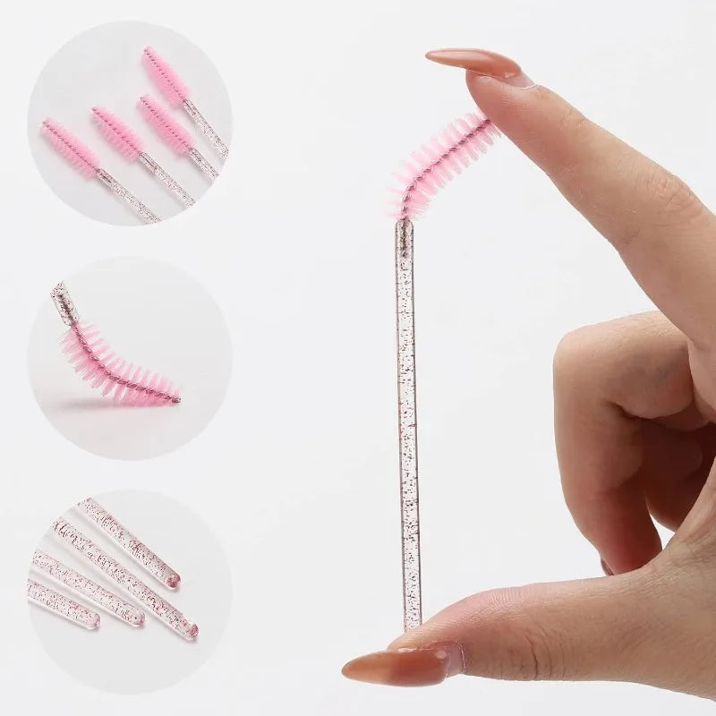 Close-up of pink and black disposable makeup brushes for eyelashes and eyebrows being held by a hand.