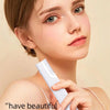 A woman is using a white sonic dermaplaning tool for eyebrow trimming and facial hair removal.