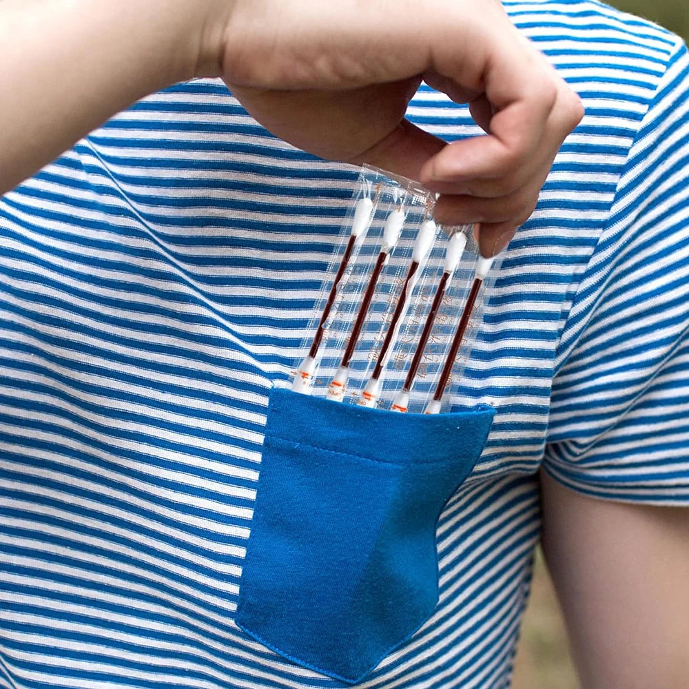 A hand holds a small blue pouch containing several instant iodine swabs for wound care.