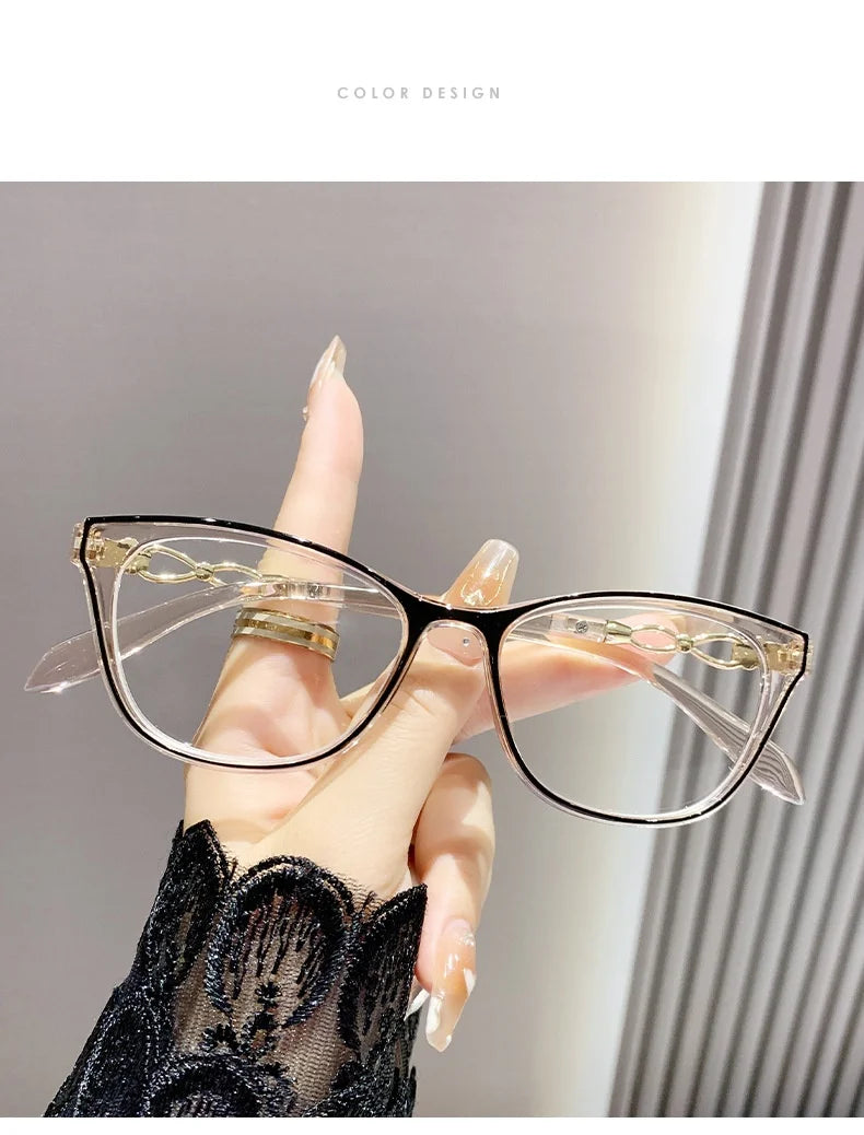 Une main tient une paire de lunettes de lecture élégantes à monture chat-œil transparentes avec des accents dorés sur un fond
