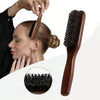 A wooden boar bristle hair brush is shown being used to style a person's hair.