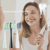 A woman is holding a replacement brush head for a sonic toothbrush, showing various sizes and colors.