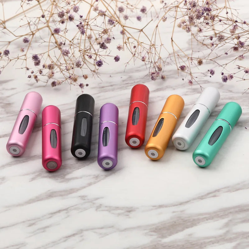 A collection of colorful portable refillable perfume bottles arranged on a white marble surface.