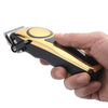 A hand holds a professional LCD hair clipper set with a black and gold body and a metal comb attachment.