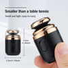 A black portable electric shaver is shown next to a hand, highlighting its small size and design.