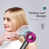 A woman is using a pink hollow-out detangling hair brush on her blonde hair.