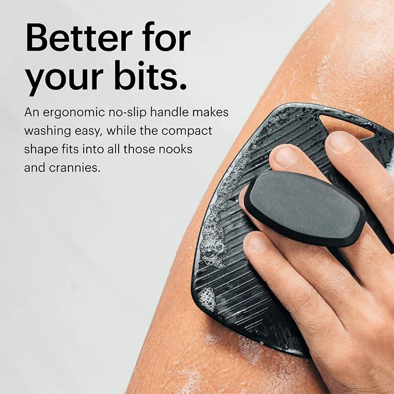 A hand is using a black silicone body scrubber on an arm, demonstrating its ergonomic design.