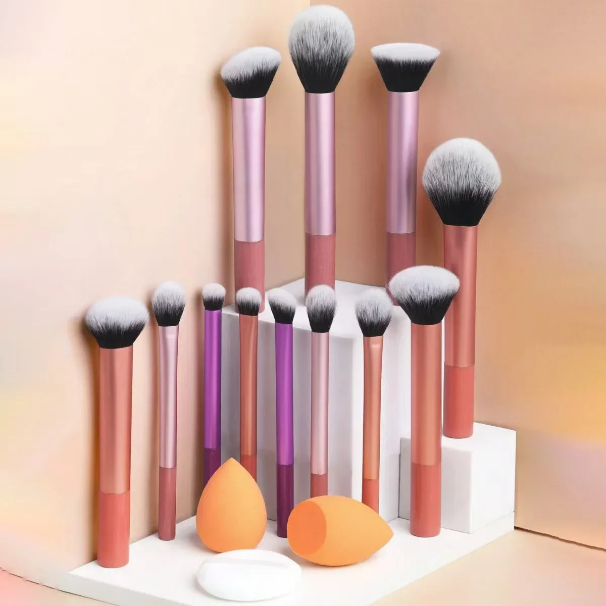 Una colección de doce brochas de maquillaje profesionales en varios tonos de rosa y púrpura exhibidas sobre una superficie bl