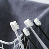 A set of white and black microbristle toothbrushes are visible inside a gray mesh holder.