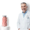 A smiling man in a lab coat holds a jar of pink memory foam earplugs.