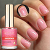 Une main tient une bouteille de durcisseur rose naturel Lily'Cute à côté d'ongles manucurés avec un vernis rose pâle.