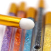 A precision applicator brush is shown dipping into a row of colorful eyelash extension cleaning bottles.