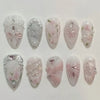 A set of 24 pink heart pearl press-on fake nails featuring floral designs and glitter accents.