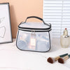 A clear cosmetic bag with a black zipper and handle sits on a white surface next to a silver perfume bottle.