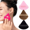 Three triangular velvet powder puffs in pink, brown, and black displayed against a woman's face.