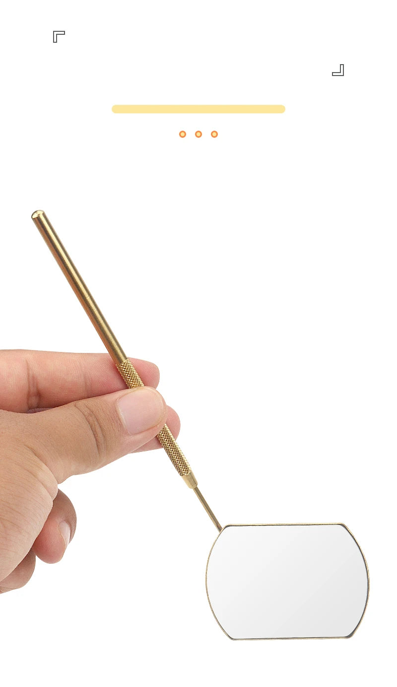 A hand holds a professional stainless steel lash extension mirror set with a gold-toned handle and a rectangular mirror plate