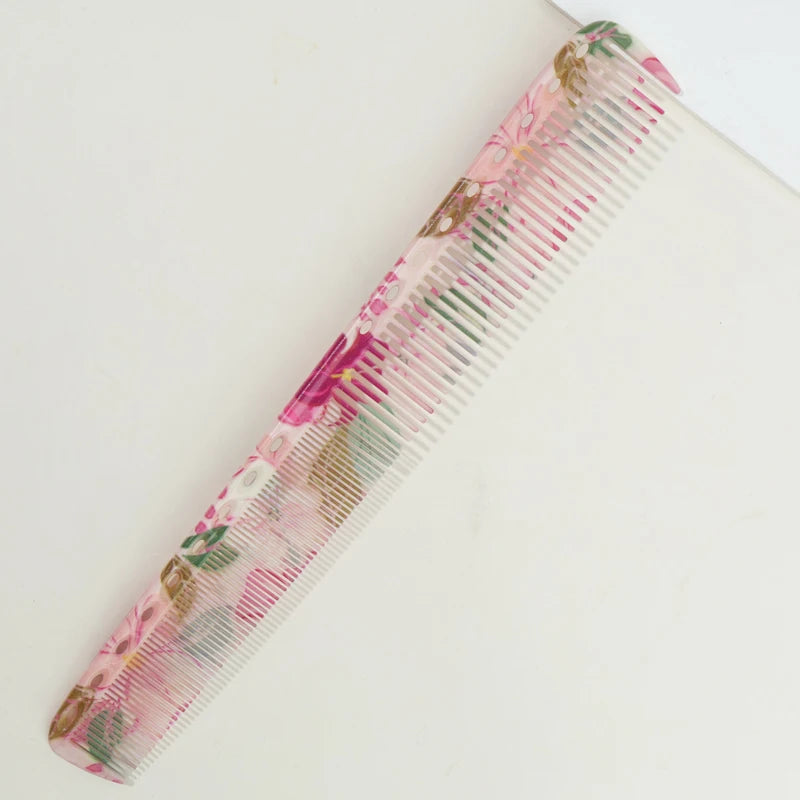 A pink and green striped plastic hair comb set with floral accents.