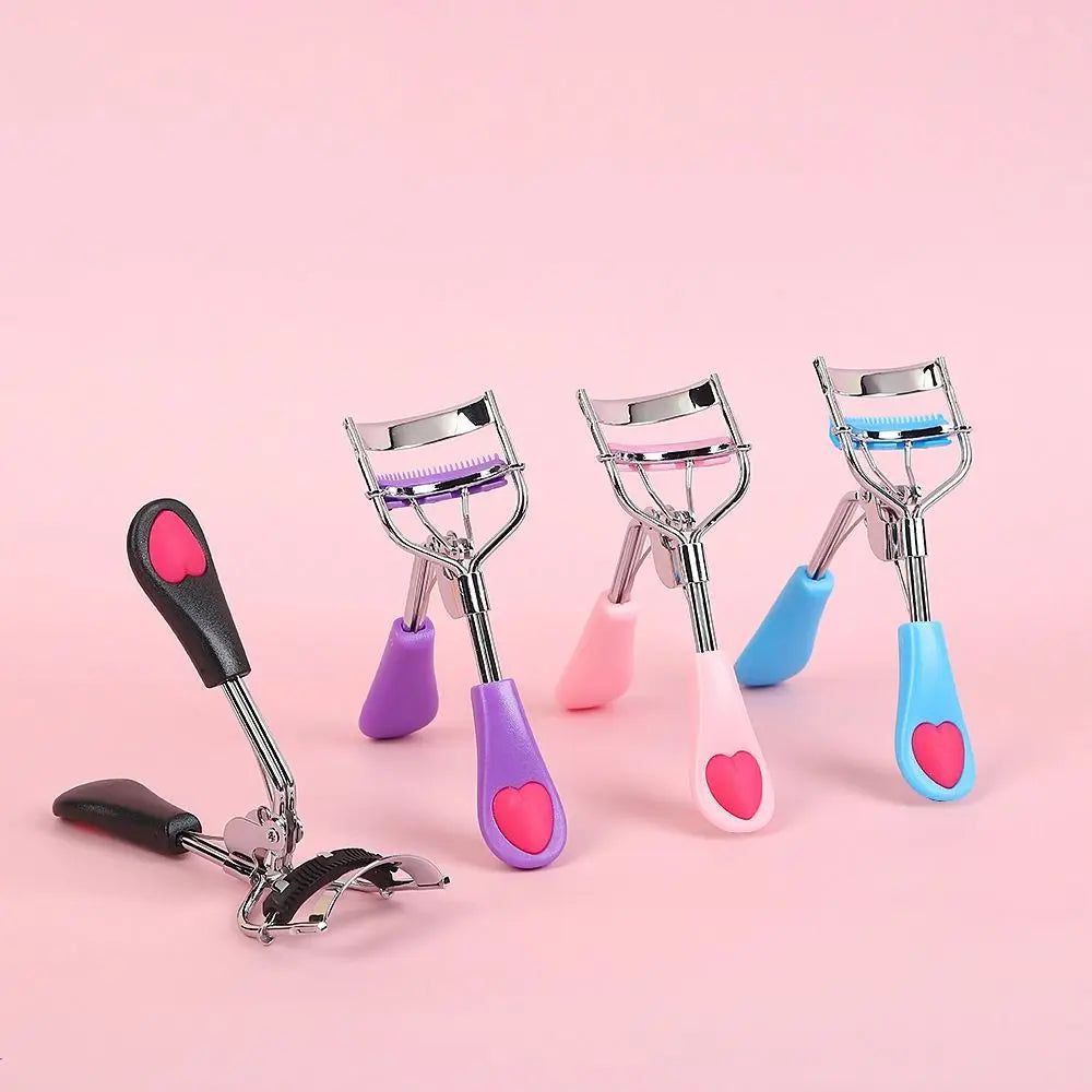 A set of five stainless steel eyelash curlers in various pastel colors including pink purple and blue displayed on a pink bac