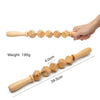 A wooden gua sha roller with a handle and multiple rounded stones, shown next to a hand for scale.