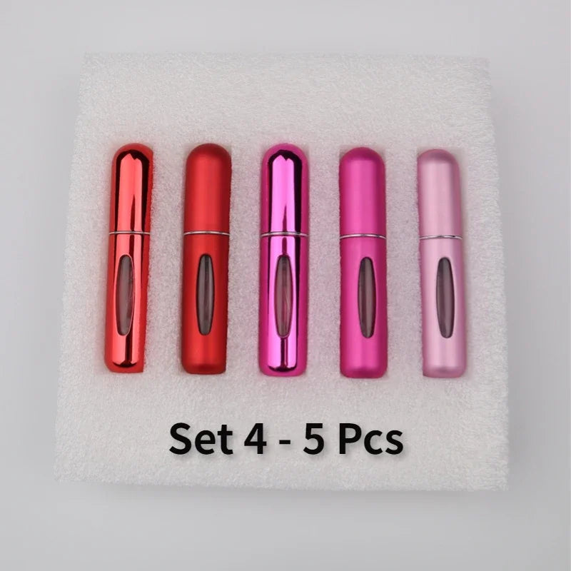 A set of five colorful, refillable mini perfume spray bottles arranged on a white, fluffy surface.
