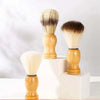 Un set de brochas de afeitar y facial de madera con cerdas rubias claras, exhibidas sobre bloques blancos.
