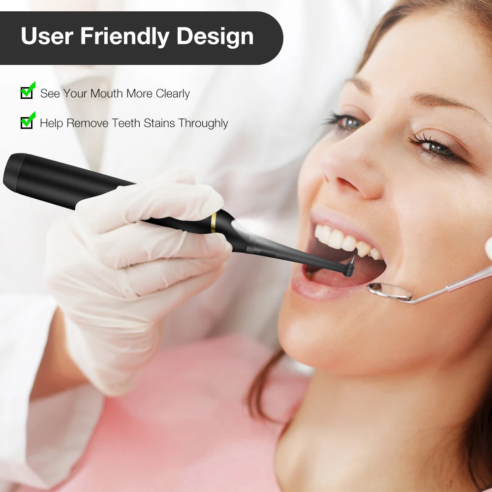 A woman wearing a white glove is using an electric dental scaler kit to clean her teeth.