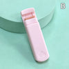 A pink cartoon mini eyelash curler is shown on a light green surface.