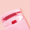 A close-up view of a pink mini folding eyelash curler set with a red interior detail.
