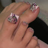 A close-up of a hand displaying press-on fake nails with short square French design and glitter accents.