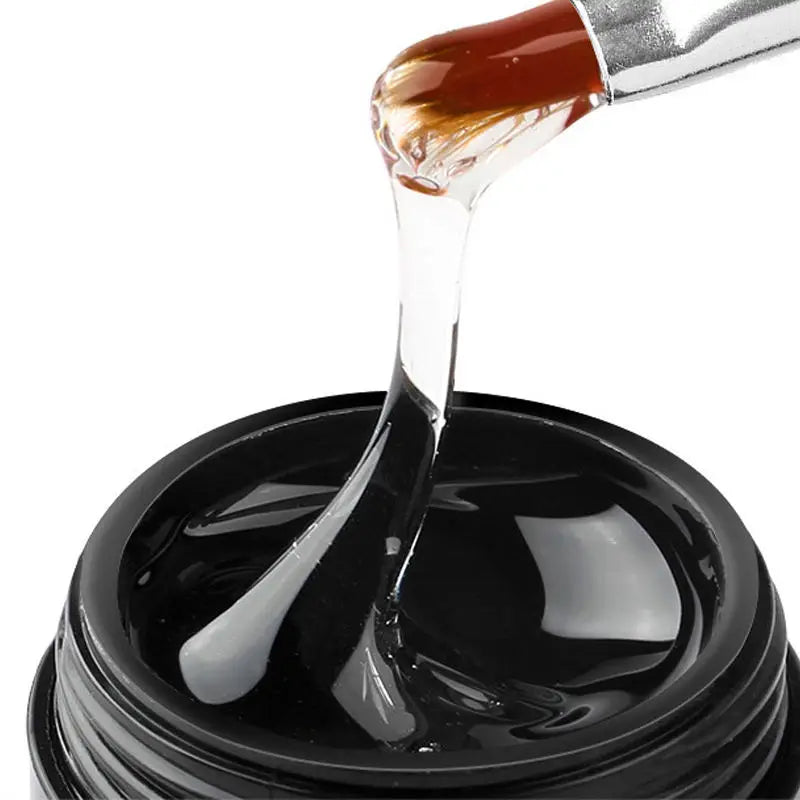 Un compte-gouttes verse un liquide clair et ambré sur une substance noire dans un bocal.