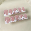 Un set de uñas postizas de perla rosa nude con puntas blancas y delicados acentos florales.