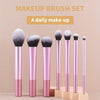 A set of seven pink makeup brushes displayed on a wooden stand for daily make-up.