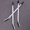 A set of white dual-ended eyelash curlers and brow brushes displayed on a gray surface.
