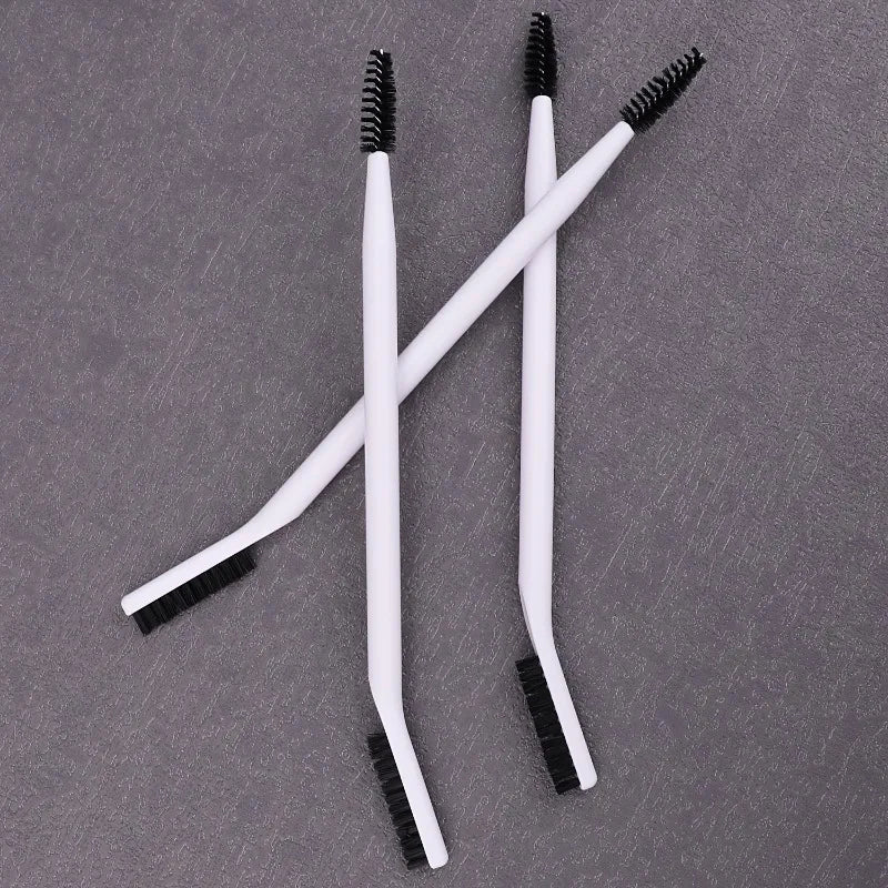 A set of white dual-ended eyelash curlers and brow brushes displayed on a gray surface.