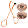A copper-toned stainless steel eyelash curler with a black pad, shown alongside close-up images of its use on an eye.