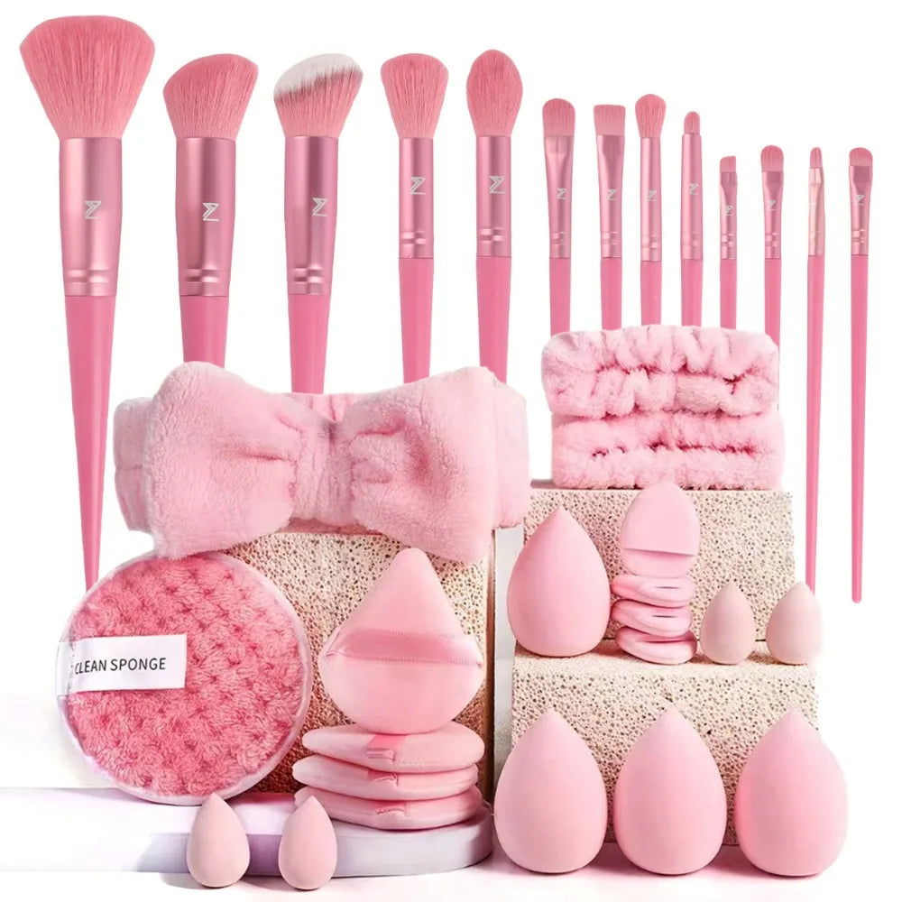 A collection of pink makeup brushes and sponges arranged on a white surface.