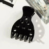 A black root lifting hair clip shaped like a hand, used for volume and bouncy curls.