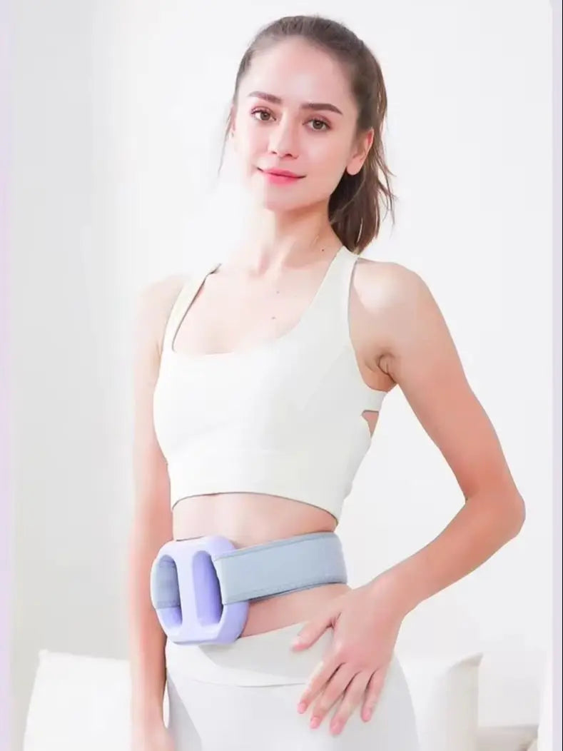 A woman is demonstrating an adjustable electric massage ring for muscle relief on her abdomen.