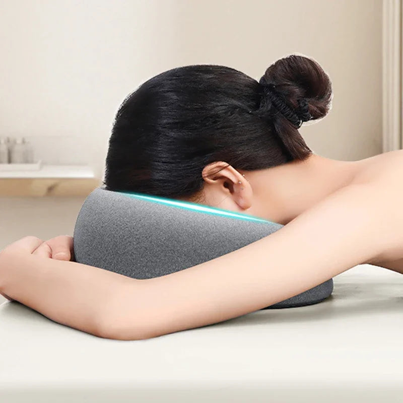 A person is resting their head on a gray ergonomic memory foam pillow with a blue light feature.