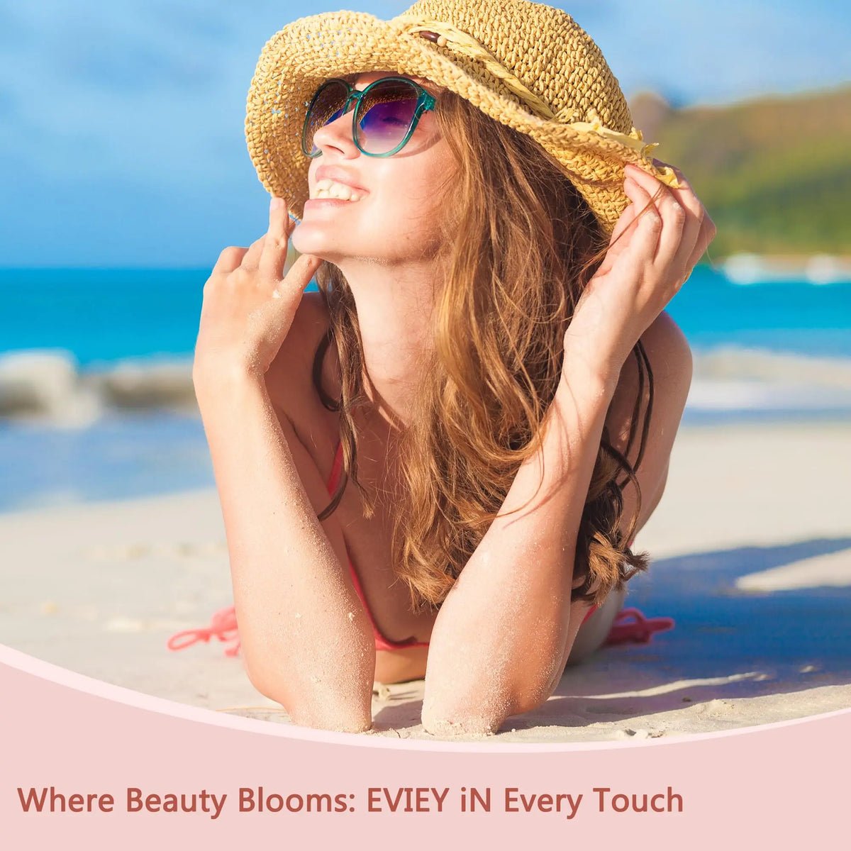 A young woman with long hair wearing a straw hat and sunglasses is relaxing on a beach, smiling.