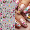 A close-up of fingernails decorated with pink and floral butterfly nail stickers for DIY decoration.