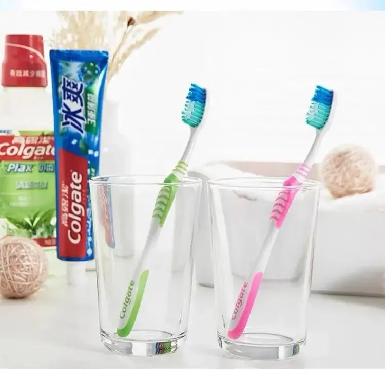 Un set de six brosses à dents Colgate et un tube de dentifrice Colgate sont présentés à côté d'un verre.