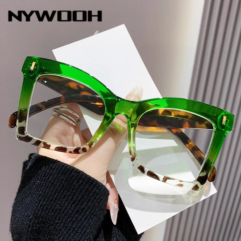 A pair of bright green square-framed reading glasses with brown and white patterned lenses being held by a person.