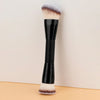 Schwarzer Make-up-Pinsel mit flauschigem, hellem braunem Haar an der Borste, aufrecht vor hellem Hintergrund.