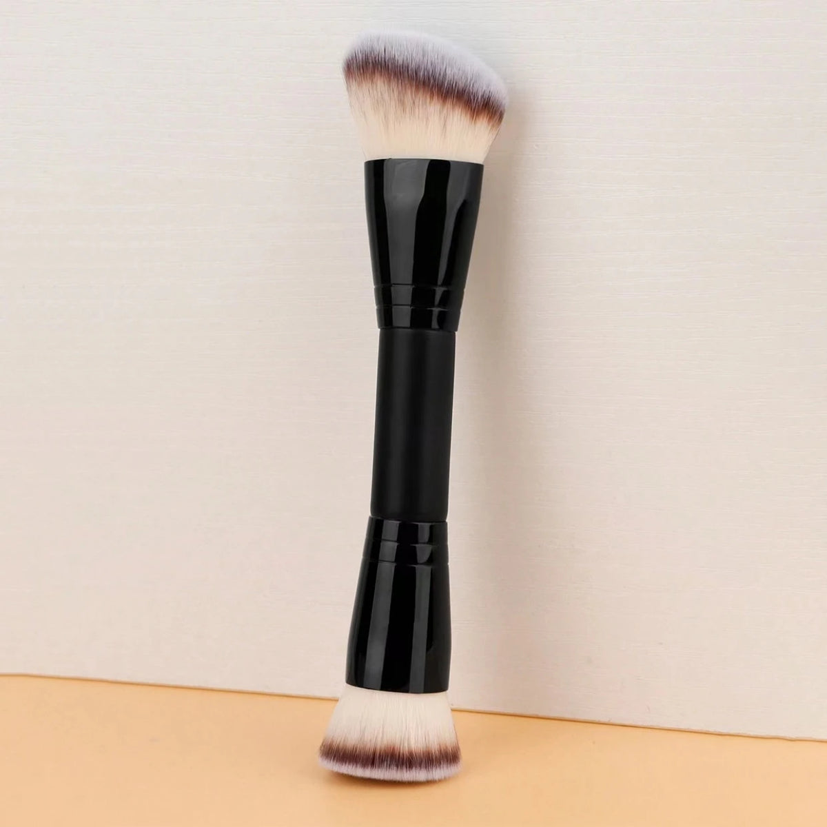 Schwarzer Make-up-Pinsel mit flauschigem, hellem braunem Haar auf der Borstenkopf, aufrecht vor hellem Hintergrund.