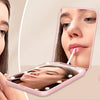 A woman uses a portable LED magnifying makeup mirror to apply makeup.