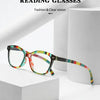 A pair of colorful retro cat eye reading glasses resting on a white box next to a white cylindrical object.